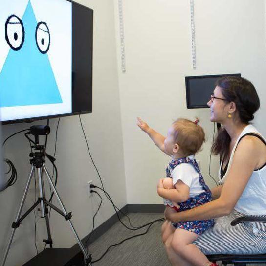 Researcher behind curtain observing child and mother engaged in activity