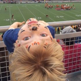 child with tiger face paint at football game