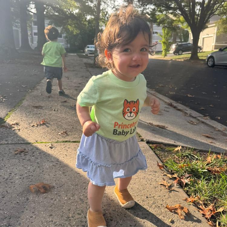 A child on the sidewalk in a Baby Lab shirt
