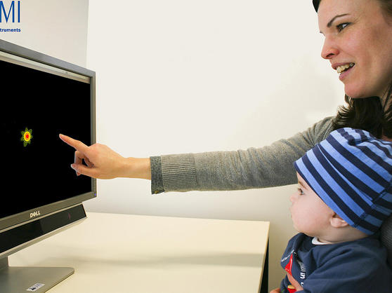 child being directed by parent to look at image on computer screen